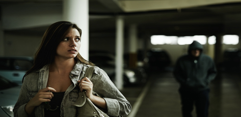 female in underground car park being followed by man in hoodie