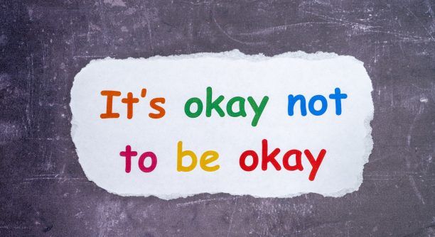 Mental  health and confidence issues with a text sign Its OK not to be OK printed on white paper and chalk board background